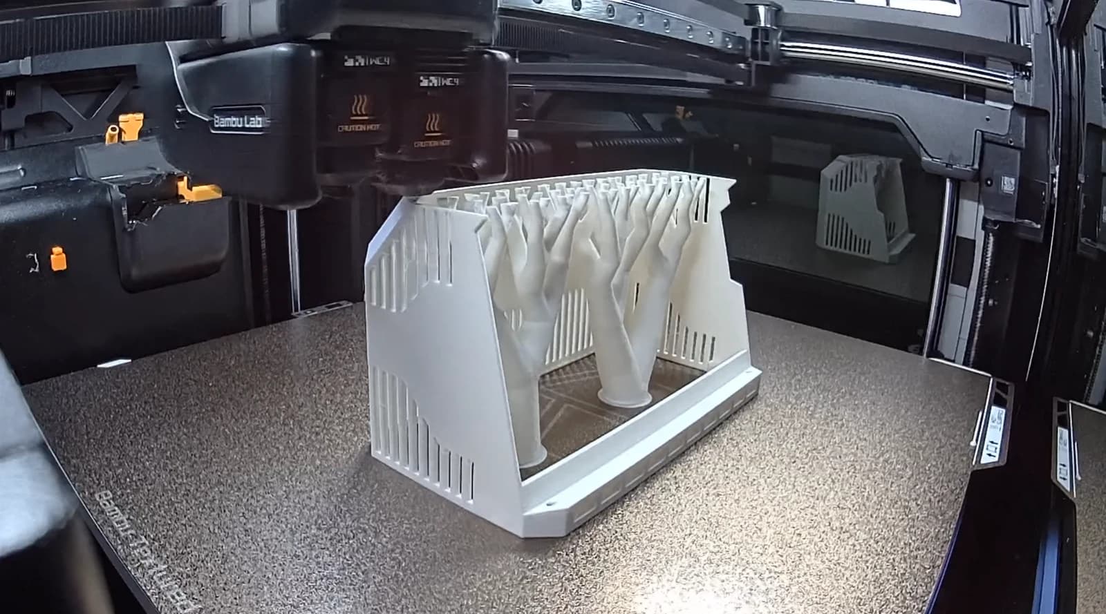 A white 7-inch Aura AQ enclosure with tree supports on a 3D printer’s build plate.