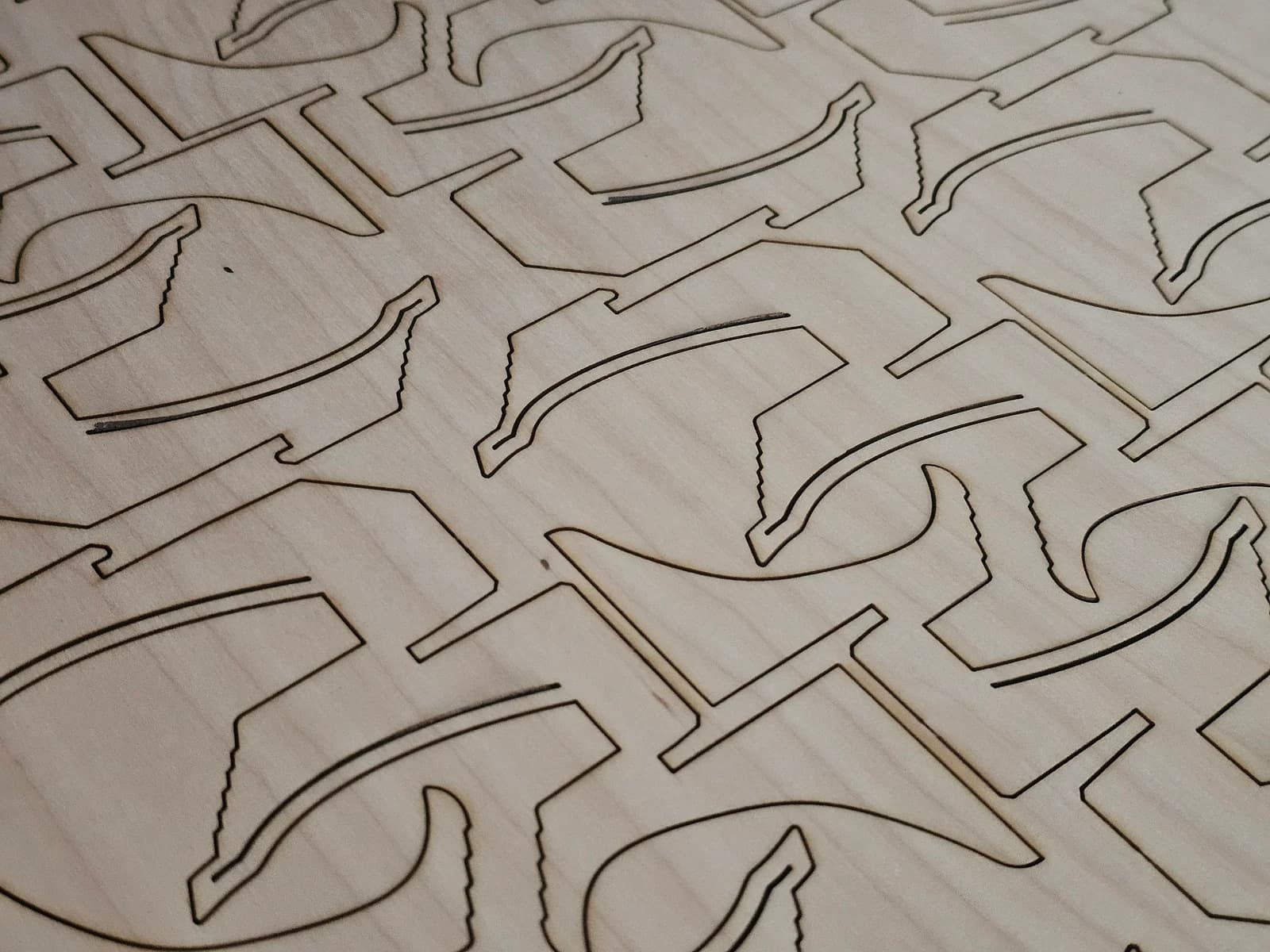 Close-up of plywood with dark laser-cut outlines around parts still in the sheet.