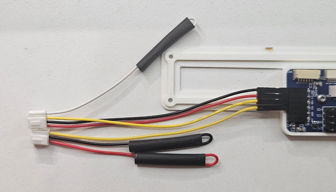 Close-up of both prepared cables connected to GND, 3.3V, SDA and SCL on the Aura PCB, with all unused contacts insulated